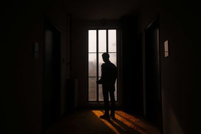 Rear view of silhouette man standing at entrance of building