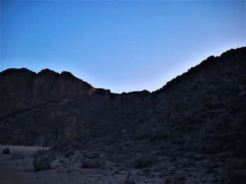 Low angle view of rocky mountains against clear blue sky