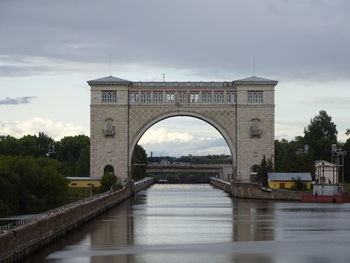 Arch bridge over river against sky