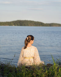 Side view of woman looking at sea against sky