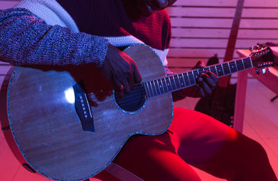 Midsection of man playing guitar