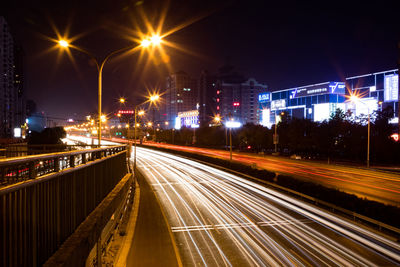 Light trails on city street against clear sky at night