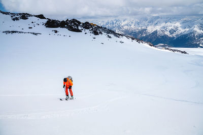 Man on skis climbs up the snow on a background of mountains