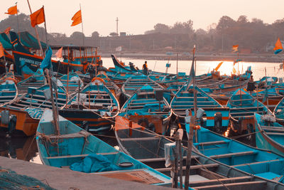 Fishing boats moored at harbor against sky