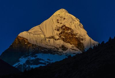 Low angle view of snowcapped mountain against blue sky