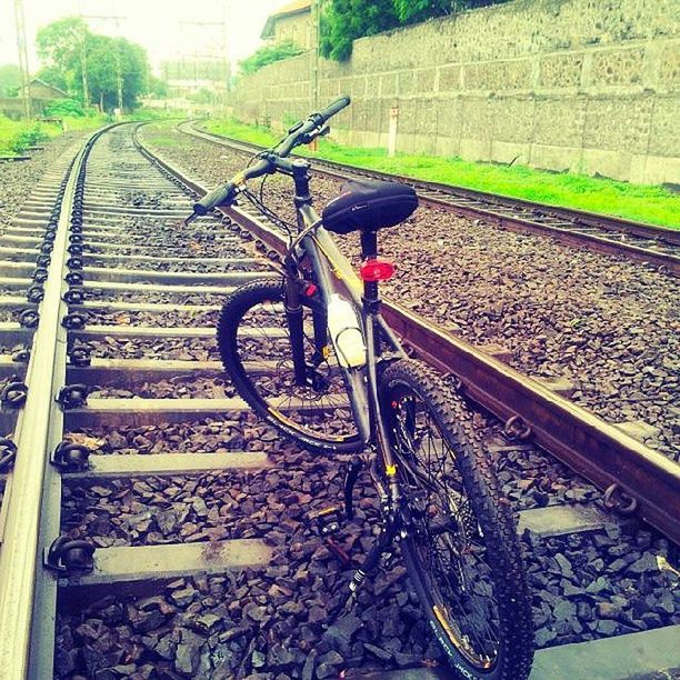 transportation, bicycle, mode of transport, land vehicle, railroad track, high angle view, day, street, outdoors, plant, diminishing perspective, building exterior, built structure, stationary, the way forward, no people, architecture, travel, wheel, rail transportation