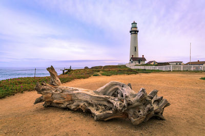 Lighthouse by sea against sky