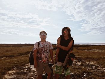 Portrait of friends standing on land against sky