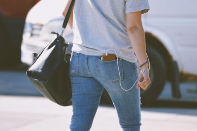 Midsection of woman walking on road in city