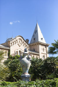 Statue amidst trees and buildings against sky