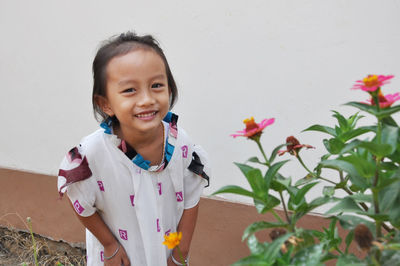 Portrait of a smiling girl standing against wall