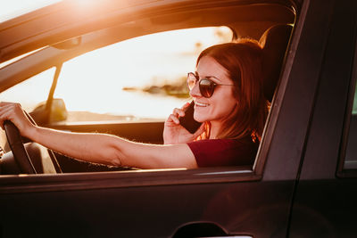 Woman sitting in car and using smartphone