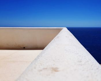 Close-up of wall against clear blue sky and sea views