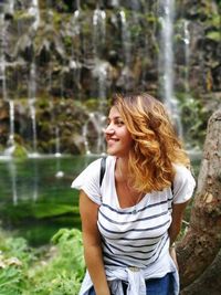 Young woman standing against trees in forest