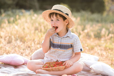 Cute boy wearing hat eating fruit