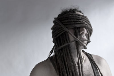 Man with face covered by dreadlocks against white background