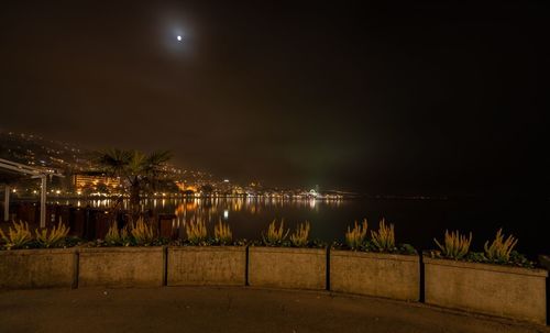 Illuminated beach against sky at night
