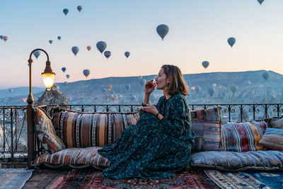 Woman drinking early morning tea with hot air balloons in cappadocia