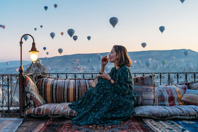 Woman looking away while sitting against sky