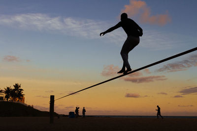 Silhouette people on beach against sky during sunset