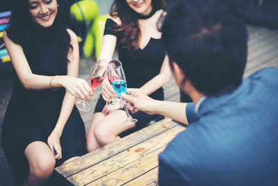 Rear view of young man with happy friends toasting drinks at bar