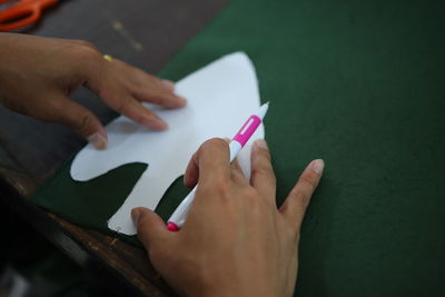 Cropped hands of person drawing with paper on table