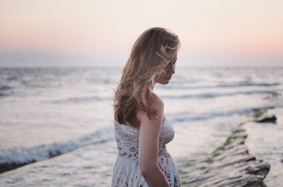 Woman standing at beach against sky