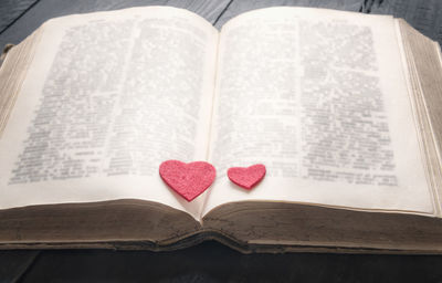 High angle view of red heart shapes on open book at table