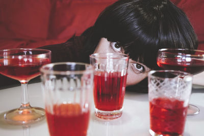 Woman resting head by glasses on table in foreground
