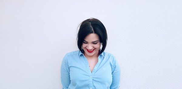 Portrait of a smiling young woman against wall