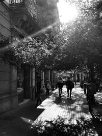 Rear view of people walking on sidewalk in city