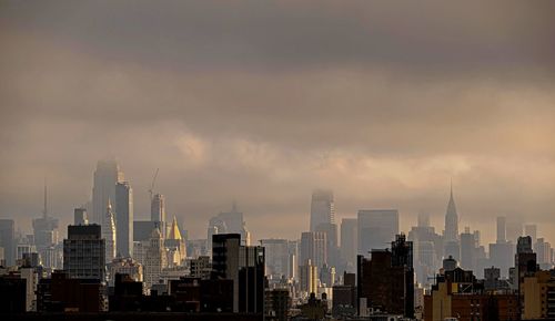 Modern buildings in city against cloudy sky