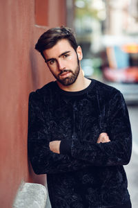 Portrait of handsome young man standing by wall