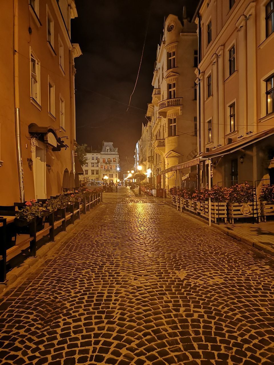 ILLUMINATED STREET AMIDST BUILDINGS AT NIGHT