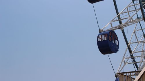 Low angle view of clock hanging against clear blue sky