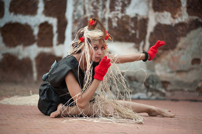 Full length of woman with arms raised against wall