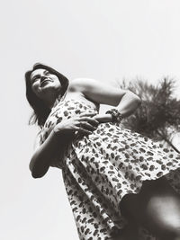 Low angle view of woman looking at camera against sky