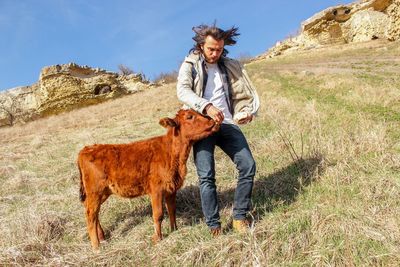 Man feeding calf on mountain