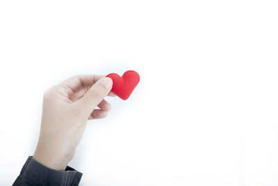 Close-up of hand holding heart shape over white background