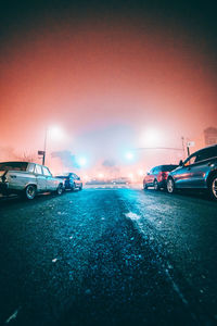 Cars on illuminated street against sky at night