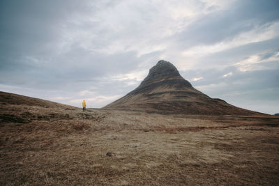 Man standing on land against mountain and sky