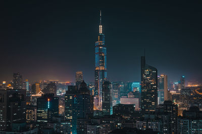 Illuminated buildings in city against sky at night