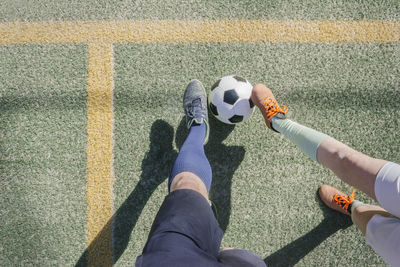 Father and son playing soccer at sports court