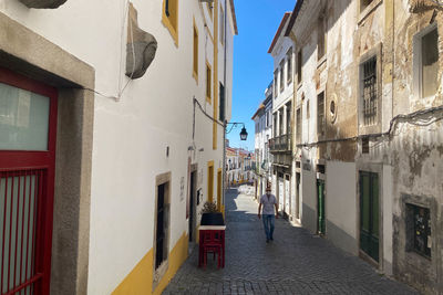 Rear view of people walking on street amidst buildings in city