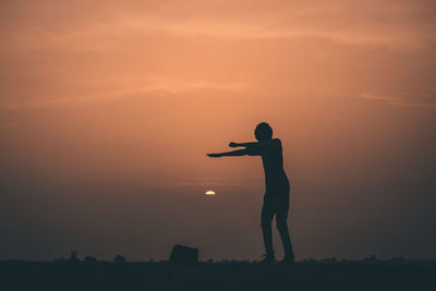 Silhouette man jumping against sky during sunset