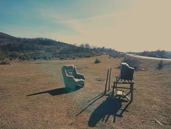 Empty chairs on field against sky