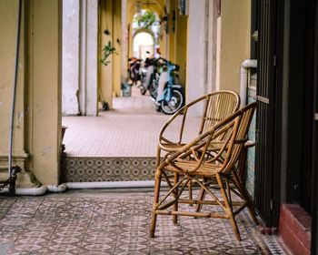 Empty wicker chairs in corridor against parked motor scooters