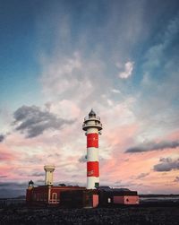 Lighthouse by building against sky