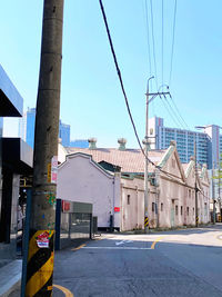 Road by buildings against clear sky