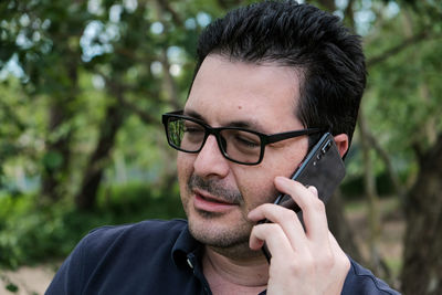 Mature man answering mobile phone outdoors